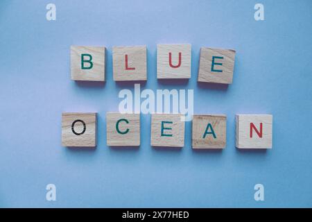 Frase oceano blu fatto di pezzi di legno su sfondo blu. Concetto di strategia aziendale. Idea di innovazione del mercato. Testo Oceano blu su sfondo blu Foto Stock