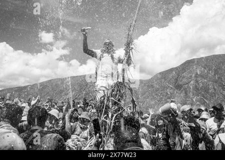 Un uomo del posto si arrampica sulla folla a Un Mojon (questo è un posto speciale che è di solito un gruppo di rocce) durante il Carnevale annuale, Maimara, Argentina. Foto Stock