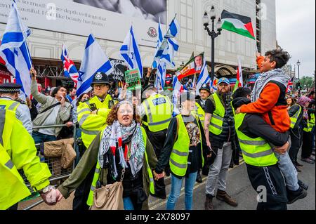 Londra, Regno Unito. 18 maggio 2024. L'enorme marcia supera di gran lunga la piccolissima controprotesta pro Israele che si trova in un angolo di Piccadilly Circus. La polizia tiene separati i due gruppi: La dimostrazione nazionale per celebrare l'anniversario della Nakba, quando centinaia di migliaia di palestinesi sono stati costretti a lasciare la loro terra per far posto allo Stato israeliano. La protesta pro Palestina, stava anche chiedendo un cessate il fuoco ora e di smettere di armare Israele. Marciò da vicino alla BBC a Whitehall. Il popolo continua a rispondere all’assalto israeliano a Gaza. La protesta è stata organizzata da Stop the War, The Pal Foto Stock