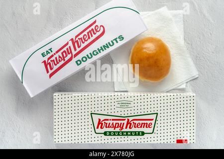 Flourtown, Pennsylvania - 15 maggio 2024: Scatola Krispy Kreme e cappello di carta con ciambella al limone su un tovagliolo di carta. Foto Stock