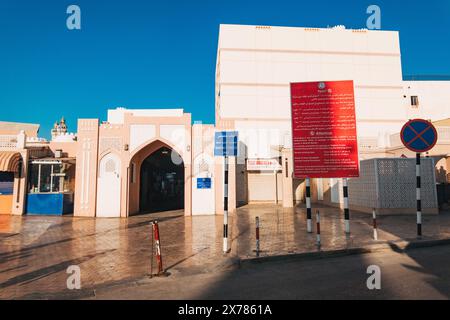 L'ingresso al Mutrah Souq, Mascate, Oman, in una tranquilla serata soleggiata. Un segno rosso con testo lungo delinea le politiche sul movimento del carrello Foto Stock