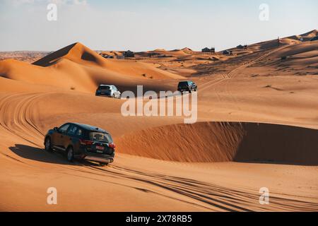 Un convoglio di veicoli 4x4 guida su dune di sabbia fino a un accampamento nel deserto a Sharqiya Sands, Oman Foto Stock