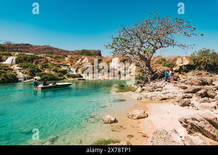 Un tour in barca naviga su uno stagno turchese a Wadi Darbat, Taqah, Oman, una popolare gita di un giorno da Salalah Foto Stock
