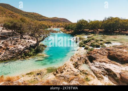 Una vibrante tonalità blu e verdi lussureggianti delle cascate a gradini di Wadi Darbat, Taqah, Oman, una popolare gita di un giorno da Salalah Foto Stock