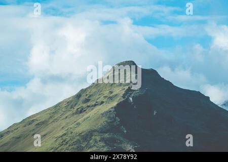 Una maestosa vetta di montagna vicino a Skogar, Islanda, sotto un cielo blu brillante con nuvole sparse. Foto Stock