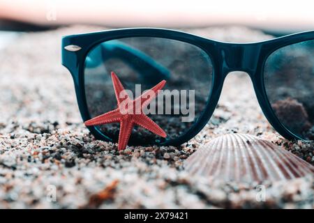 Occhiali da sole con stelle marine rosse sulla spiaggia di sabbia Foto Stock