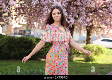 Bella donna vicino agli alberi in fiore il giorno di primavera Foto Stock