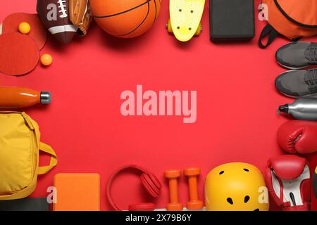 Telaio realizzato con diverse attrezzature sportive su sfondo rosso, piatto. Spazio per il testo Foto Stock