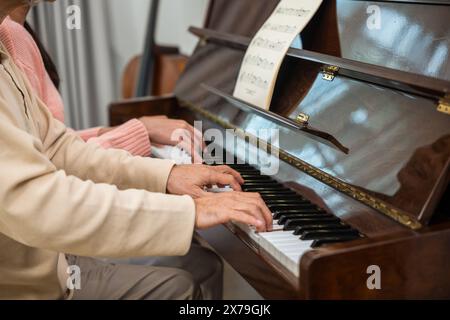 Giovane donna che insegna pianoforte per l'insegnamento di alto uomo Foto Stock