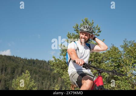 Ciclista in mountain bike in sella a una bicicletta elettrica lungo un sentiero di ghiaia bianca in una giornata estiva di sole. Concetto di attività sportiva all'aperto. Foto Stock