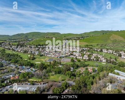 Vista aerea delle case suburbane e delle lussureggianti colline verdi di Clayton, California, con il Monte Diablo sullo sfondo sotto cieli azzurri. Foto Stock