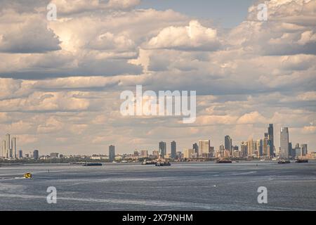 New York, NY, Stati Uniti - 1° agosto 2023: Skyline del New Jersey e di Manhattan con la statua di Miss Liberty al centro vista dalla baia di Narrows sotto la densa cl blu Foto Stock