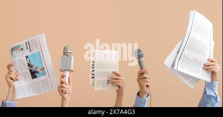 Mani femminili con microfoni e giornali su sfondo beige Foto Stock