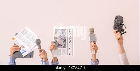 Mani femminili con giornali e microfoni su sfondo chiaro Foto Stock