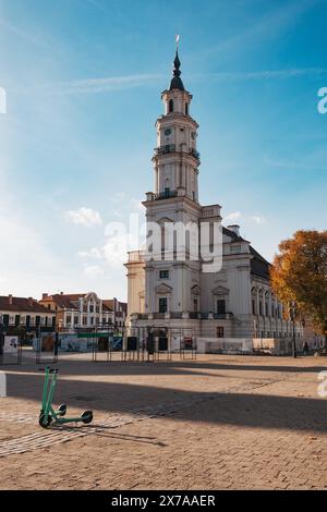 Una piazza vuota di fronte al municipio di Kaunas, Lituania, in una soleggiata mattinata d'autunno. Uno scooter Bolt Share è parcheggiato sui ciottoli Foto Stock