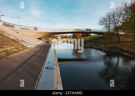 Un sentiero pedonale e un ponte su una sezione del fiume Nemunas a Kaunas, in Lituania, in una tranquilla mattinata d'autunno Foto Stock