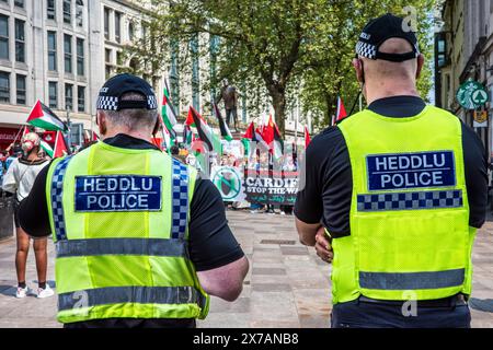 Due agenti di polizia che guardano un manifestante pro-palestinese in una manifestazione di strada anti-Israele - campagna di solidarietà palestinese. Centro di Cardiff. Foto Stock