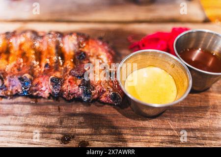 Costolette di maiale grigliate con senape e salsa di pomodoro su una tavola di legno. Messa a fuoco selezionata. Foto di alta qualità Foto Stock