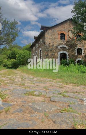 La foto è stata scattata in Ucraina. La foto mostra un vecchio fienile di pietra sul lato di una strada rurale acciottolata. Foto Stock