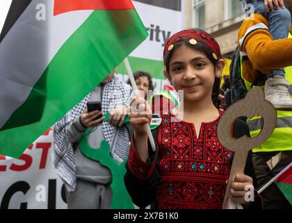 Londra, Regno Unito. 18 maggio 2024: Una giovane ragazza vestita con abiti tradizionali palestinesi tiene una "chiave palestinese" e una bandiera alla Nakba 76 marzo per la Palestina contro gli attacchi israeliani a Gaza nel centro di Londra, Regno Unito. Una grande marcia ha segnato il 76° anniversario della "catastrofe palestinese” nel 1948 e ha chiesto un cessate il fuoco a Gaza. Foto Stock