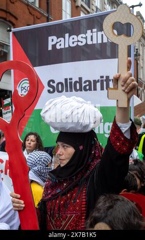 Londra, Regno Unito. 18 maggio 2024: Una donna vestita con abiti tradizionali palestinesi tiene "chiavi palestinesi" alla Nakba 76 marzo per la Palestina contro gli attacchi israeliani a Gaza nel centro di Londra, Regno Unito. Una grande marcia ha segnato il 76° anniversario della "catastrofe palestinese” nel 1948 e ha chiesto un cessate il fuoco a Gaza. Foto Stock