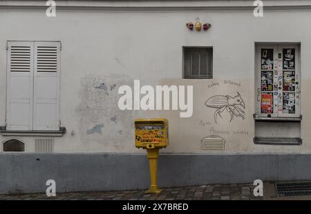 Francia, Parigi - 3 gennaio 2024 - tapparelle e finestre con un piccolo spioncino sulla vecchia parete di una residenza al piano terra e cassetta postale. Una stretta strada acciottolata Foto Stock