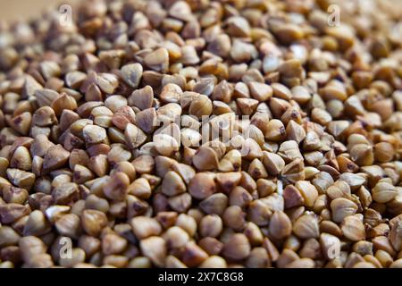 Pile di grano saraceno crudo. Grano saraceno che riempie la cornice, perfetto per temi culinari e di salute. Foto Stock