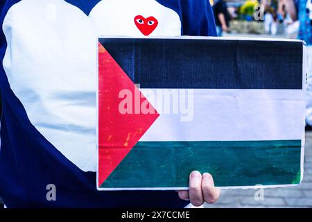 Un manifestante tiene in mano un cartello con la bandiera palestinese mentre indossa una felpa a cuore d'amore durante la manifestazione. I manifestanti pro-palestinesi tengono una dimostrazione di morte in Piazza del Castello di Varsavia. In commemorazione della Nakba a partire dal 1948, i manifestanti sono rimasti immobile sul terreno. In seguito un certo numero di palestinesi e polacchi-palestinesi raccontarono le loro storie al pubblico riunito. Foto Stock