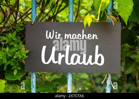 Immagine simbolo delle festività aziendali: Insegna sul giardino con l'iscrizione tedesca WIR MACHEN URLAUB (siamo in vacanza) Foto Stock