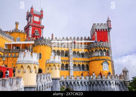 Facciata colorata con i quartieri reali e la torre dell'orologio rosso presso il Palácio da pena o lo storico castello del palazzo Palácio da pena a Sintra, Portogallo. Il castello da favola è considerato uno dei migliori esempi di architettura romanticistica portoghese del XIX secolo al mondo. Foto Stock