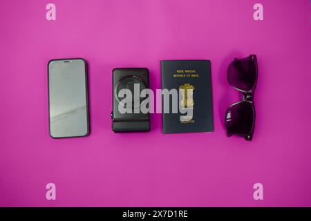 Passaporto indiano, occhiali da sole aviatore e un moderno smartphone disposti su un vivace sfondo rosa. Perfetto per i viaggi Foto Stock