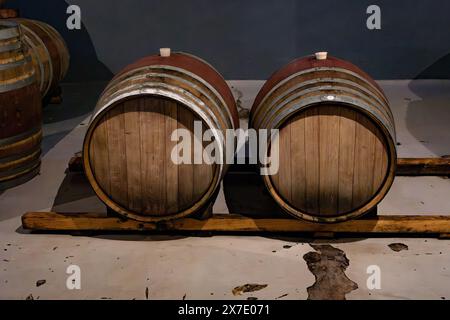 Due botti di vino di rovere in cantina sorrette da travi di rovere per evitare che tocchino il pavimento. Foto Stock