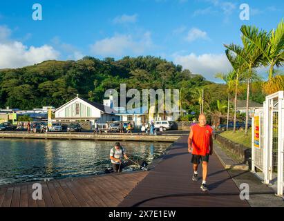 Uomo con una camicia rossa che cammina nel porto di Uturoa, città principale dell'isola di Raiatea, Isole della società, Polinesia francese Foto Stock