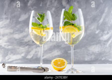 Cocktail Hugo Spritz rinfrescante con cordiali di fiori di sambuco e spumante in bicchieri su cemento Foto Stock