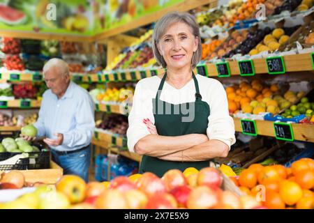 Donna lavoratore supermercato impilare frutta su scaffale in sala di vendita Foto Stock