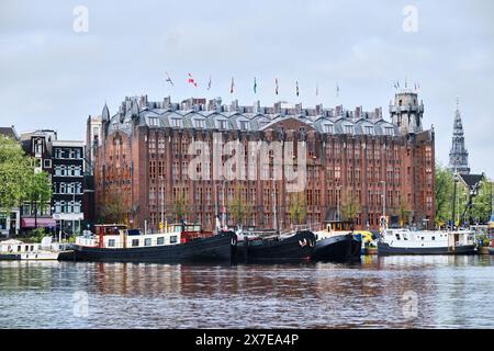 Paesi Bassi, Amsterdam - 8 aprile 2024: Grand Amrath Hotel Amsterdam e barche sul fiume Foto Stock