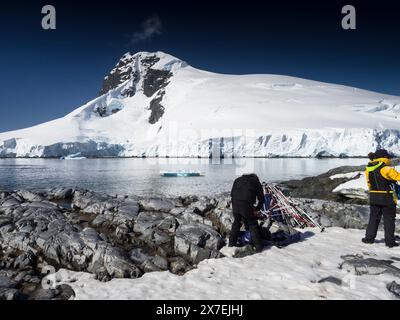 Le guide della spedizione si preparano sulla spiaggia di Palaver Point, due isole Hummock con Buache Peak in Antartide Foto Stock