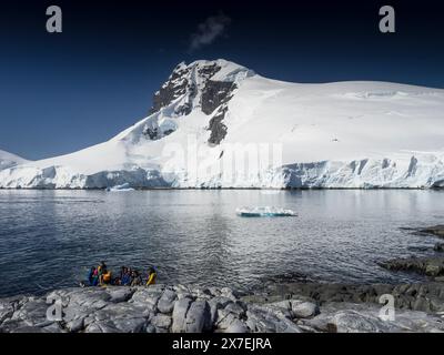 Uno zodiaco pieno di turisti atterra a Palaver Point con Buache Peak sullo sfondo, due isole Hummock, Antartide Foto Stock