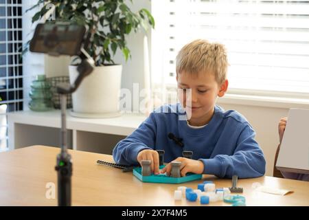 Boy gioca a un nuovo gioco da tavolo per il proprio blog, registrando una sessione di gioco divertente e interattiva Foto Stock
