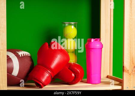 Ripiani con diverse attrezzature sportive contro il muro verde Foto Stock