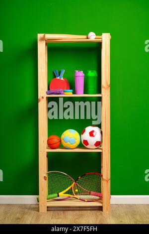 Ripiani con diverse attrezzature sportive contro il muro verde Foto Stock
