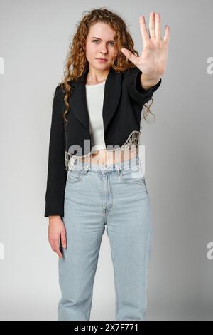Donna con capelli ricci che tiene la mano in alto Foto Stock