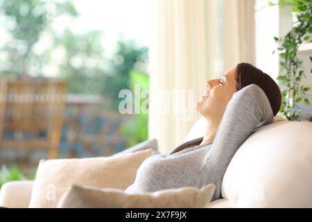 Profilo di una donna felice che riposa su un divano a casa Foto Stock