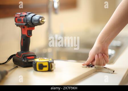 Donna che assembla a mano mobili da cucina in cucina a casa Foto Stock