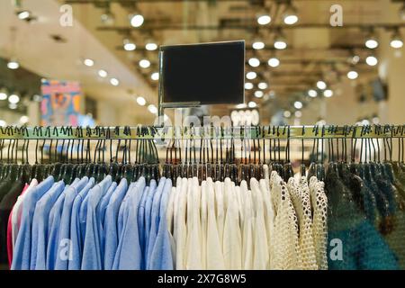 Vestiti su appendiabiti con un cartello nero per il testo in un negozio al dettaglio . Centro commerciale e di moda Foto Stock