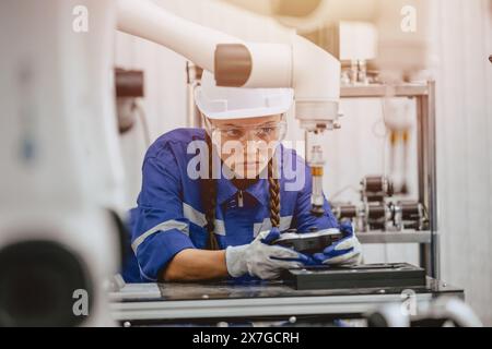 Ingegnere donne studentesse universitarie imparare a controllare manualmente il braccio robotico industriale con telecomando in classe di laboratori di robotica in tecnologia poliedrica Foto Stock