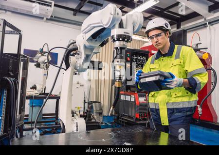 Ingegnere giovane studente universitario impara a controllare il braccio di saldatura robotizzato del settore in classe di laboratorio di ingegneri robotici nel politecnico Foto Stock