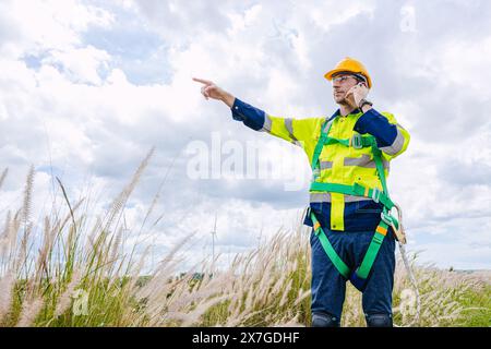 il controllo maschio dell'ingegnere opera sul campo manutenzione esterna del servizio generatore eolico. mano del lavoratore che punta la posizione al gesto dell'ordine Foto Stock