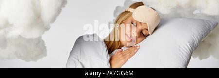Una donna bionda in intimo pigiama che dorme tranquillamente su un cuscino tra soffici nuvole. Foto Stock