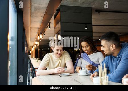Un gruppo eterogeneo di colleghi di un team di startup che si gusta un caffè insieme intorno a un tavolo in uno spazio di coworking. Foto Stock